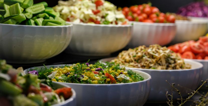 Several bowls filled with colorful fresh salads and vegetables on display.