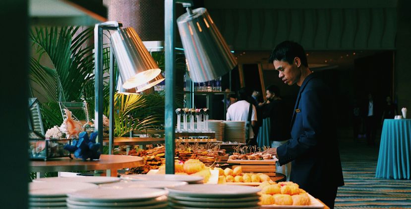 A man in a dark suit examines a buffet table filled with various snacks and desserts.