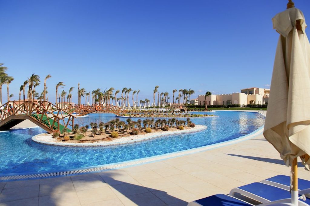 Colourful cocktails lined up beside a swimming pool at sunset in an all-inclusive resort setting