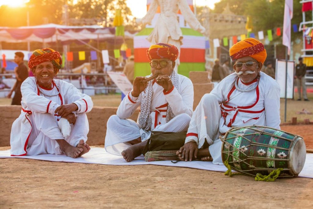 Three traditional musicians in colourful turbans performing music at a cultural festival in India