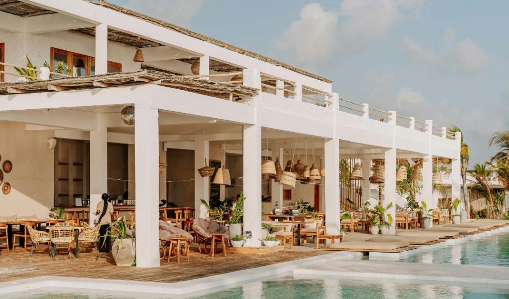 Open-air restaurant and pool area at a modern resort with white architecture and wooden terraces