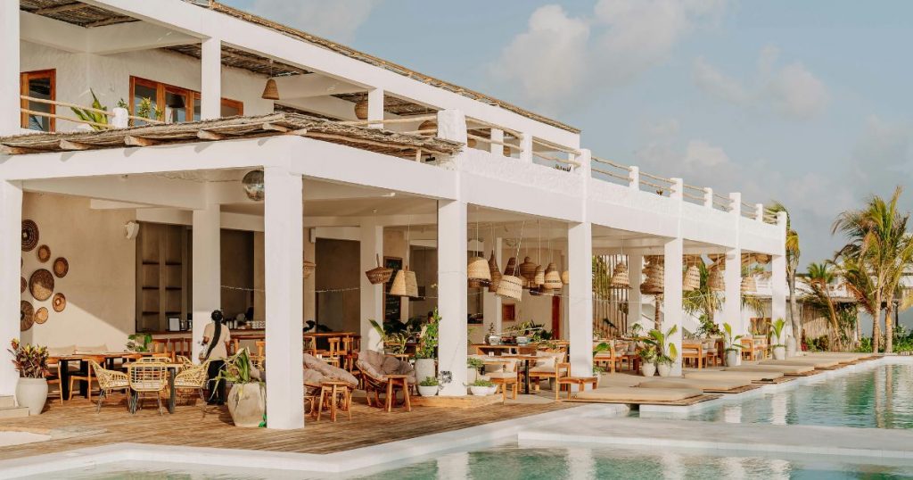 Open-air restaurant and pool area at a modern resort with white architecture and wooden terraces
