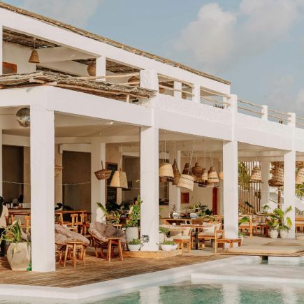 Open-air restaurant and pool area at a modern resort with white architecture and wooden terraces